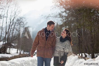 Happy couple walking on sunny snowy footpath
