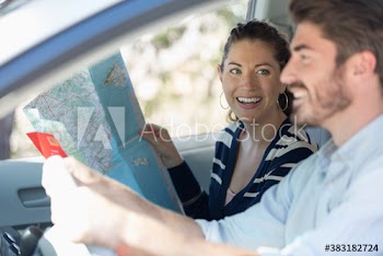 Happy couple with map on road trip in car