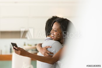 Happy couple with smart phone hugging