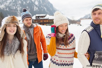 Happy couples friends walking outside snowy lodge