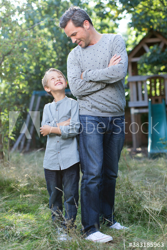 Happy father and son standing back to back