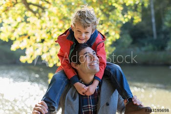 Happy father carrying son on shoulders at riverside