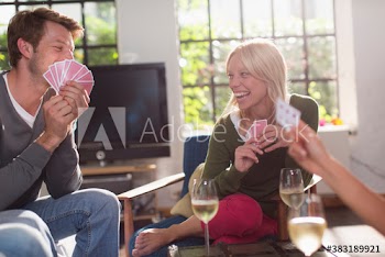 Happy friends playing cards and drinking wine