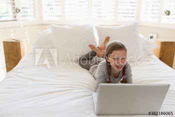 Happy girl using laptop on bed