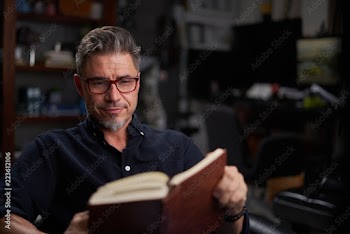 Happy good-looking older man reading book at home