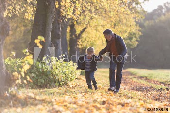 Happy grandfather and grandson running in sunny autumn park