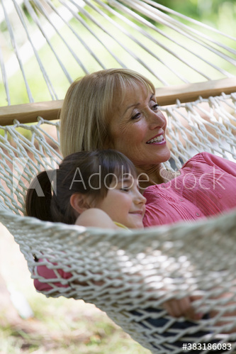Happy grandmother and granddaughter relaxing in hammock