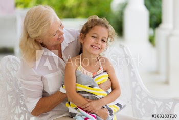 Happy grandmother holding granddaughter wrapped in towel on patio