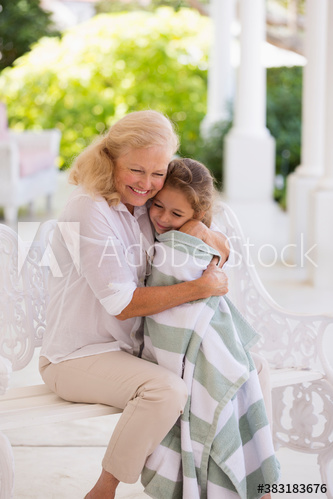 Happy grandmother hugging granddaughter in towel on patio