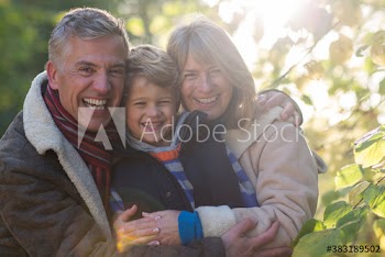 Happy grandparents and grandson hugging in park