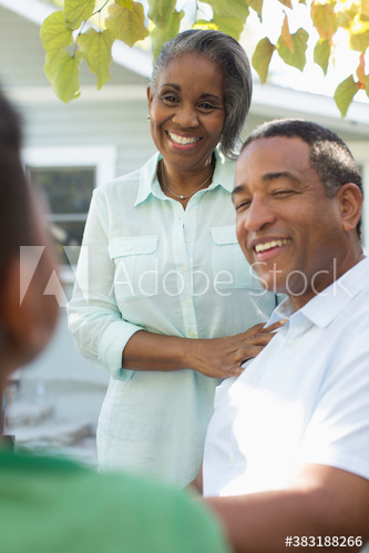 Happy grandparents talking to grandson on patio