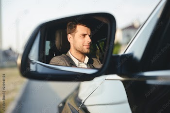 Happy handsome young business man driver in his car