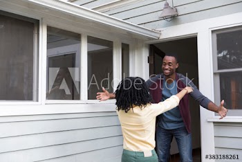Happy husband greeting wife with hug at doorway