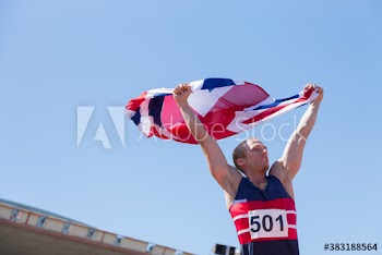 Happy male track and field athlete celebrating with British flag