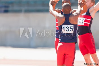 Happy male track and field team celebrating on sunny running track