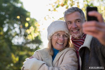 Happy mature couple taking selfie with smart phone in park