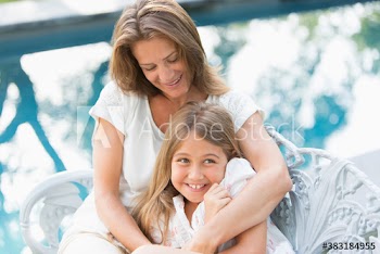 Happy mother and daughter hugging at poolside