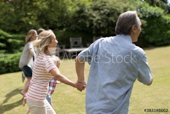 Happy multi-generation family running in sunny garden