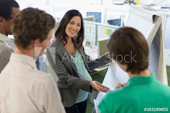 Happy pregnant businesswoman leading meeting at flipchart in office