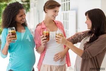 Happy pregnant women friends drinking iced tea