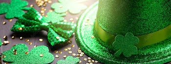 Happy Saint Patrick's Day web banner with traditional symbols, shamrock, green attire. Green hat, bow tie, St Patricks Day shamrocks, golden confetti on dark wooden background, copy space