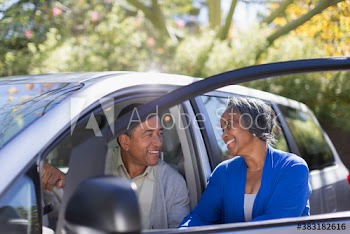 Happy senior couple at car door