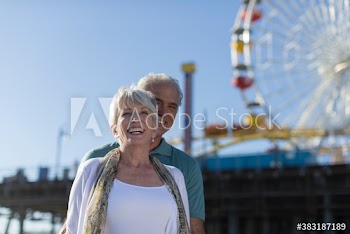 Happy senior couple below Ferris Wheel, Santa Monica, Los Angeles
