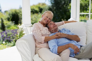 Happy senior couple cuddling on patio sofa