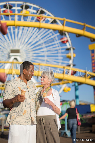 Happy senior couple eating ice cream cones at amusement park