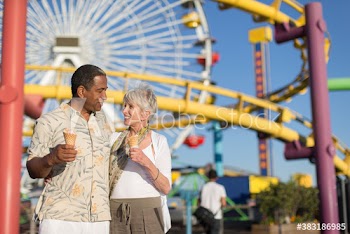 Happy senior couple eating ice cream cones at sunny amusement park