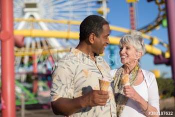 Happy senior couple enjoying ice cream cones at amusement park