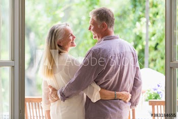 Happy senior couple hugging in patio doorway