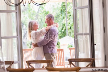 Happy senior couple hugging in patio doorway