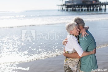 Happy senior couple hugging on sunny ocean beach