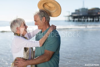 Happy senior couple hugging on sunny ocean beach