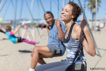 Happy senior couple on swing set on sunny beach