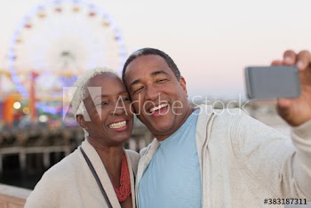 Happy senior couple taking selfie at amusement park