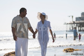 Happy senior couple walking on sunny ocean beach