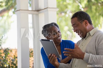 Happy senior couple with digital tablet laughing on porch