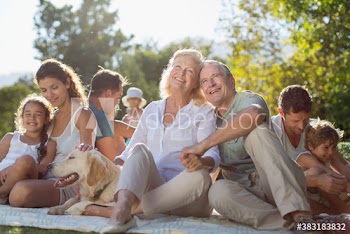 Happy senior couple with multi-generation family in sunny backyard