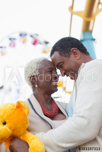 Happy senior couple with teddy bear at amusement park