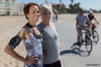 Happy senior female joggers on sunny boardwalk