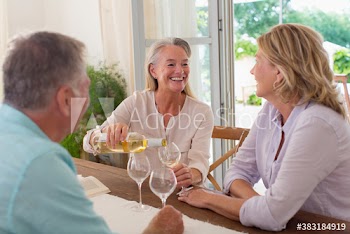 Happy senior friends enjoying white wine at table