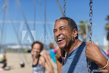 Happy senior man on swing set on sunny beach