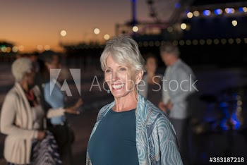 Happy senior woman on beach with friends at night