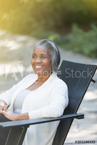 Happy senior woman relaxing in adirondack chair on patio