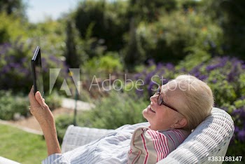 Happy senior woman suing digital tablet in sunny garden