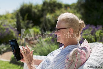 Happy senior woman using digital tablet in sunny garden