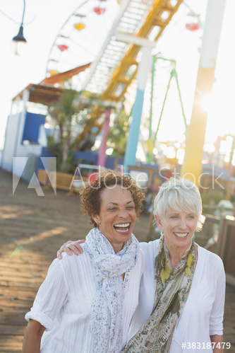 Happy senior women friends at sunny amusement park