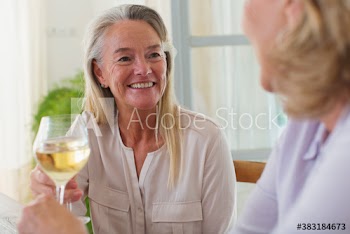 Happy senior women friends enjoying white wine